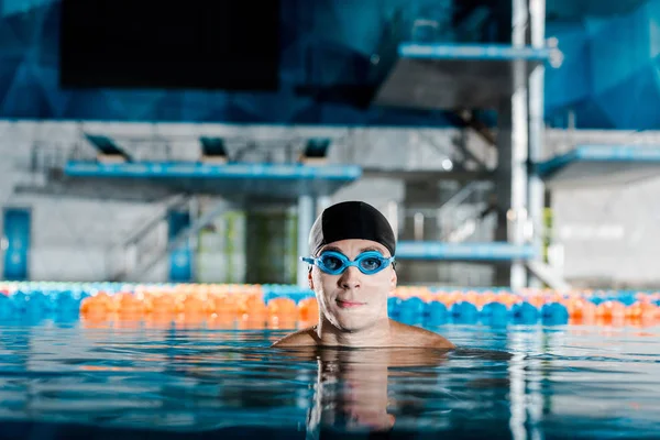 Nadador en googles y gorra de natación mirando a la cámara - foto de stock