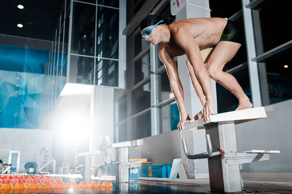 Nadador sin camisa de pie en la postura inicial en el bloque de buceo - foto de stock