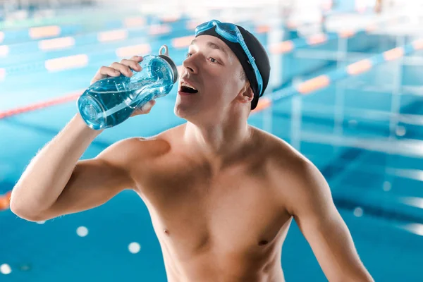 Apuesto nadador bebiendo de deportes botella - foto de stock