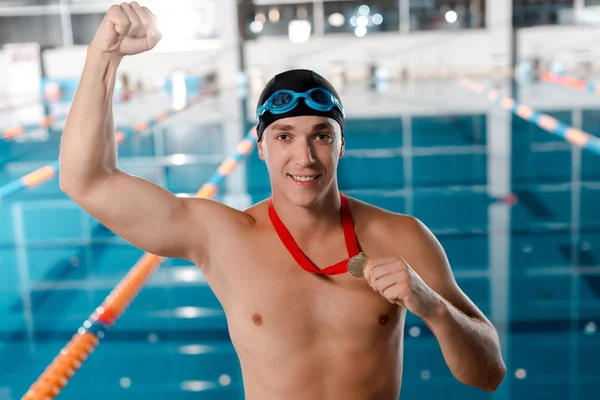 Allegro campione in cuffia da nuoto gesticolando mentre tiene medaglia d'oro — Foto stock