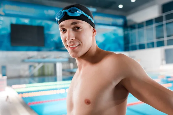 Nadador feliz en gafas y gorra de natación mirando a la cámara - foto de stock