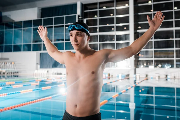 Без рубашки спортсмен стоит с протянутыми руками возле бассейна — стоковое фото