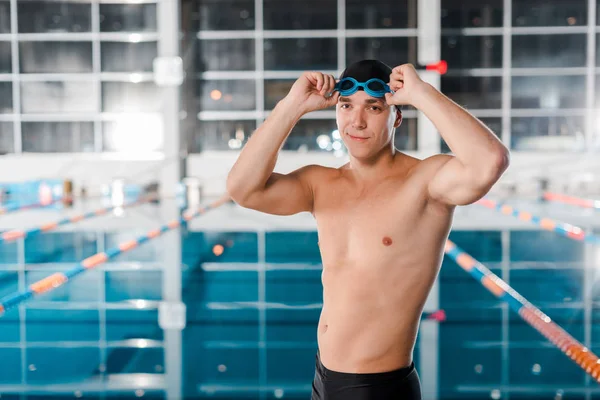 Nadador atlético feliz tocando gafas cerca de la piscina - foto de stock