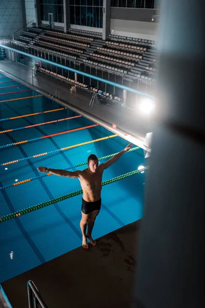 Vue grand angle du nageur debout avec les mains au-dessus de la tête près de la piscine — Photo de stock