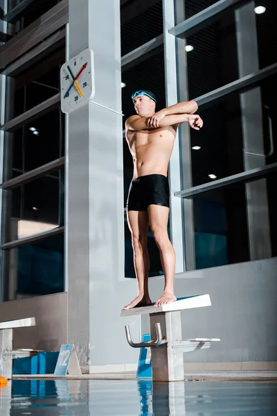 Schöne und hemdlose Schwimmerin wärmt sich in der Nähe des Schwimmbades auf — Stockfoto