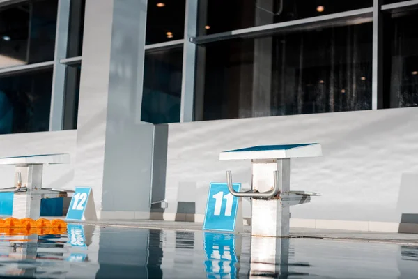 Signs with numbers near diving blocks in swimming pool — Stock Photo