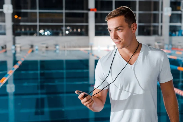 Felice allenatore tenendo timer vicino alla piscina — Foto stock