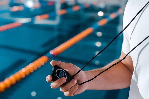 Cropped view of trainer holding timer near swimming pool — Stock Photo