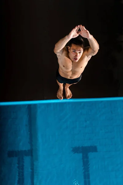 Blick von oben auf eine gut aussehende Schwimmerin, die mit ausgestreckten Händen in der Nähe des Schwimmbades steht — Stockfoto