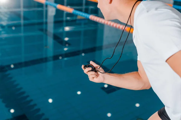 Cropped view of athletic trainer holding timer near swimming pool — Stock Photo
