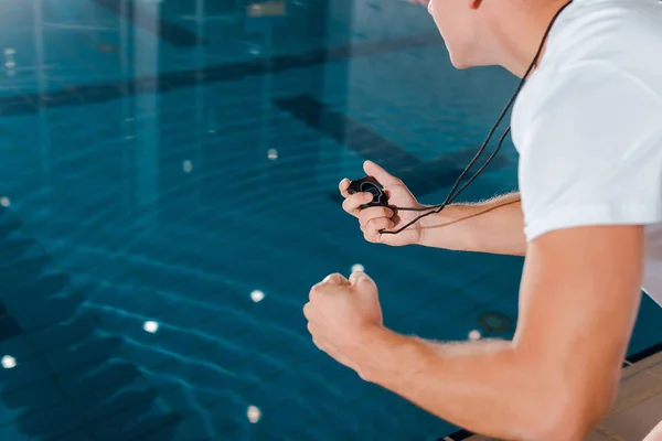 Vista recortada de entrenador deportivo con temporizador cerca de la piscina - foto de stock