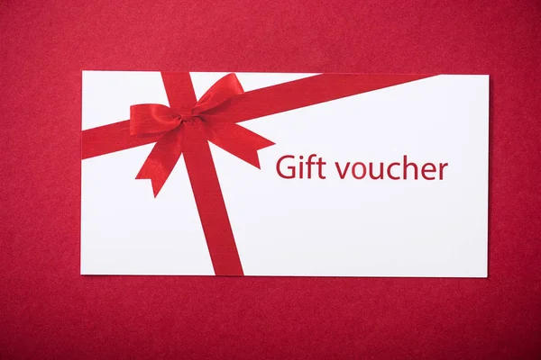 Top view of white gift voucher on red surface — Stock Photo