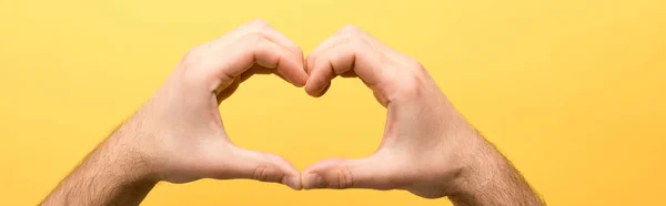 Panoramic shot of man showing heart gesture isolated on yellow — Stock Photo