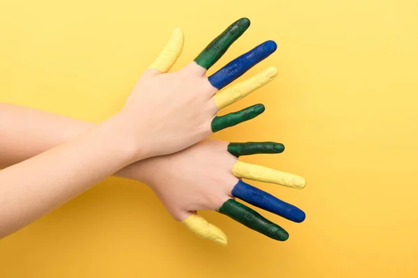 Vista recortada de la mujer que muestra los dedos de colores sobre fondo amarillo - foto de stock