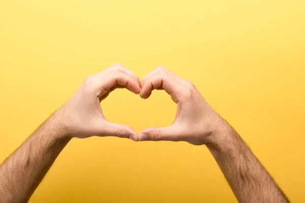 Vista cortada do homem mostrando gesto do coração no fundo amarelo — Fotografia de Stock