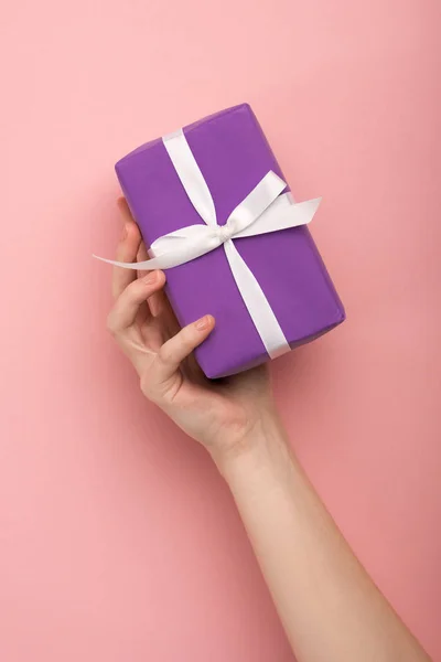 Vista recortada de la mujer sosteniendo regalo sobre fondo rosa - foto de stock