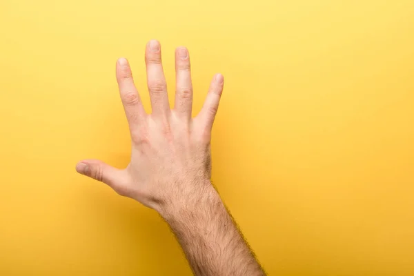 Vista recortada del hombre mostrando cinco dedos sobre fondo amarillo - foto de stock