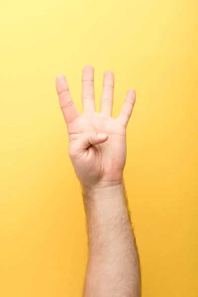 Vista recortada del hombre mostrando cuatro dedos sobre fondo amarillo - foto de stock