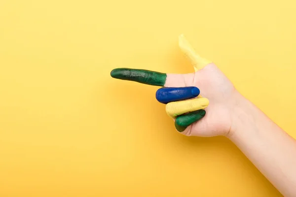 Abgeschnittene Ansicht einer Frau, die mit dem Finger auf gelbem Hintergrund zeigt — Stockfoto