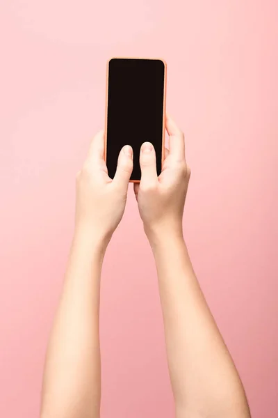 Обрізаний вид жінки, що тримає смартфон ізольовано на рожевому — стокове фото