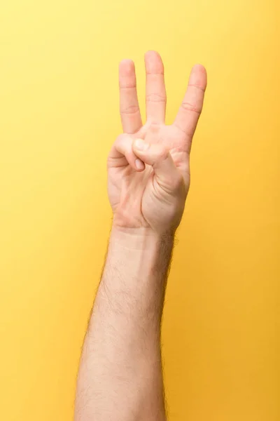 Vista ritagliata di uomo che mostra tre dita su sfondo giallo — Foto stock