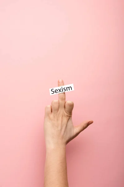 Vue recadrée de la femme montrant majeur et carte avec lettrage sexisme sur fond rose — Photo de stock