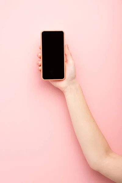 Vista recortada de la mujer sosteniendo teléfono inteligente sobre fondo rosa - foto de stock