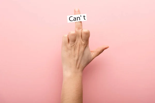 Cropped view of woman showing middle finger and card with cant lettering on pink background — Stock Photo