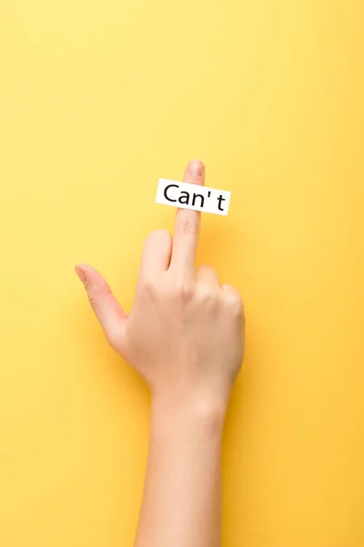 Cropped view of woman showing middle finger and card with cant lettering on yellow background — Stock Photo