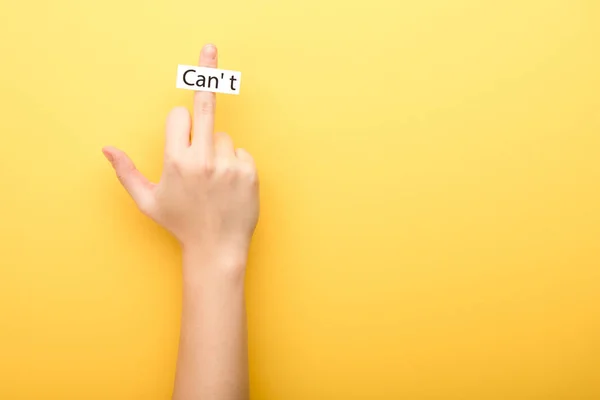 Vista recortada de la mujer que muestra el dedo medio y la tarjeta con letras de cant sobre fondo amarillo - foto de stock