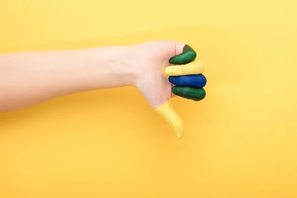 Cropped view of woman with colorful fingers showing dislike on yellow background — Stock Photo