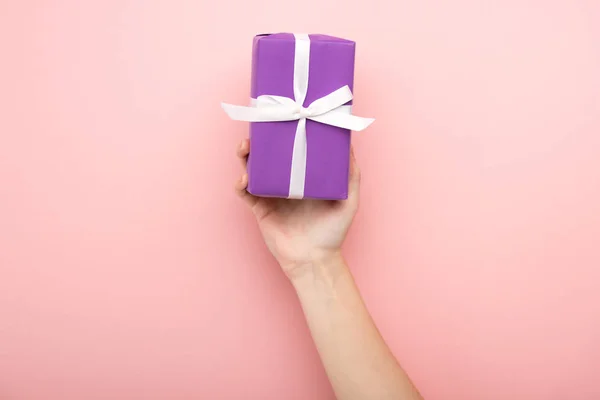 Cropped view of woman holding gift on pink background — Stock Photo