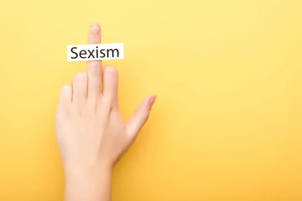 Cropped view of man showing middle finger with card sexism isolated on yellow — Stock Photo