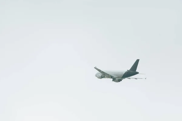 Vista de ángulo bajo del avión comercial aterrizando en el cielo nublado - foto de stock