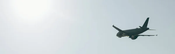 Foto panorámica de avión en cielo despejado con luz solar - foto de stock