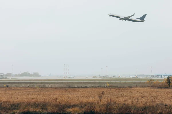 Partenza di volo di aereo su campo d'aviazione con cielo nuvoloso su sfondo — Foto stock