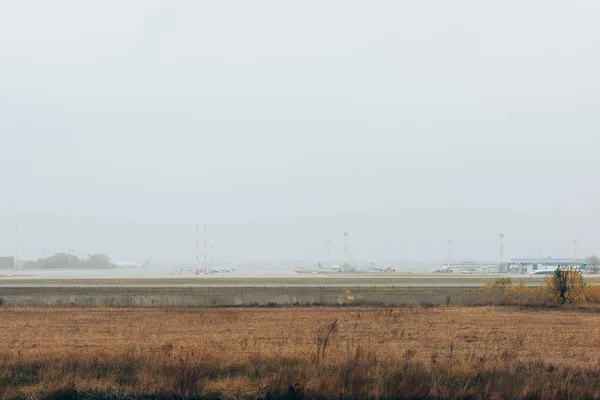 Pista del aeropuerto con campo de hierba y cielo nublado - foto de stock