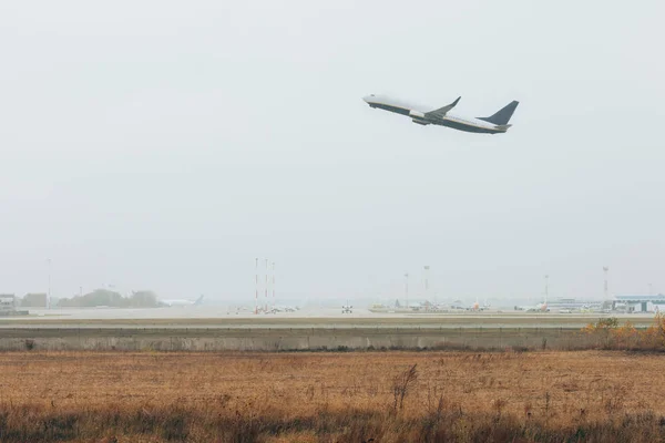 Flugzeug hebt im Himmel über nebligem Flugplatz ab — Stockfoto