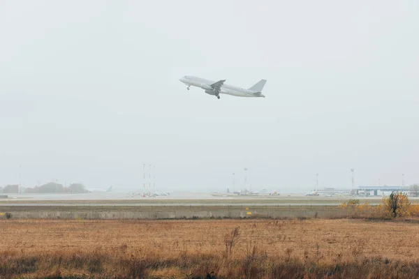 Avião pousando acima do aeródromo gasoso com céu nublado — Stock Photo