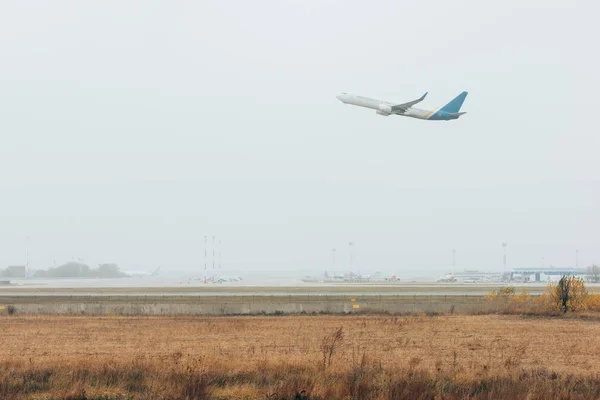 Partenza in aereo in cielo nuvoloso sopra campo d'aviazione con pista — Foto stock