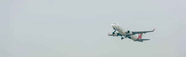 Tiro panorâmico de avião comercial no céu nublado — Fotografia de Stock