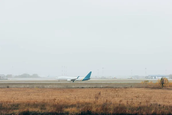 Самолёт приземляется на взлетно-посадочной полосе аэропорта с облачным небом на заднем плане — стоковое фото