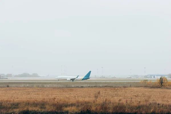 Airplane landing on airport runway with cloudy sky at background — Stock Photo