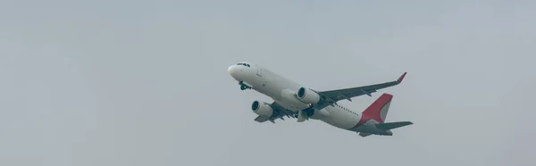 Panoramic shot of airplane in cloudy sky — Stock Photo