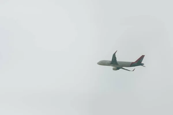 Vista en ángulo bajo de la salida de vuelo del avión en cielo nublado - foto de stock