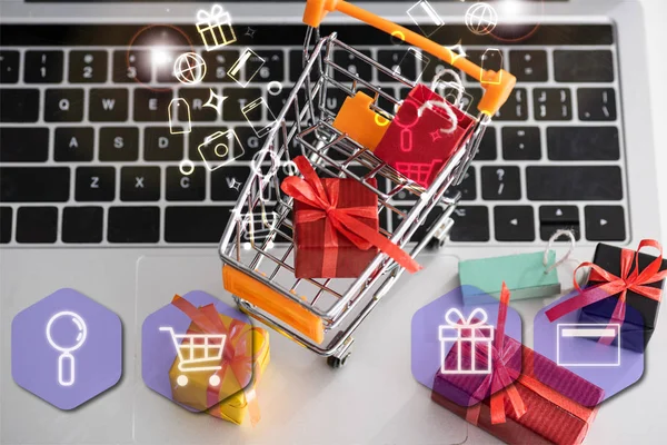 Top view of toy gift boxes with cart and illustration on laptop — Stock Photo