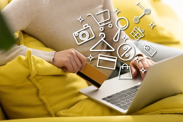 Cropped view of woman holding credit card and using laptop near illustration — Stock Photo