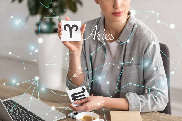 Cropped view of astrologer showing cards with zodiac signs near constellations and aries lettering — Stock Photo