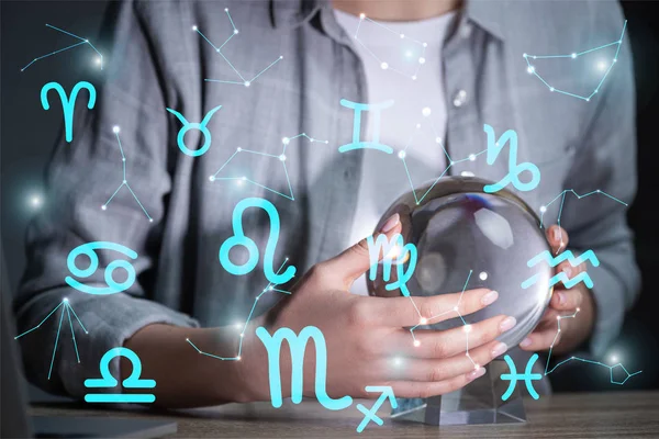 Vista recortada de la mujer usando bola de cristal al lado de constelaciones y signos del zodíaco - foto de stock