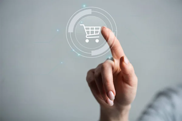 Cropped view of woman pointing with finger on cart isolated on grey — Stock Photo